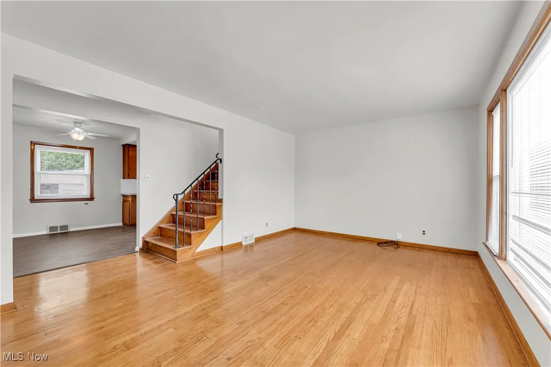 Spare room featuring light wood-style floors, stairs, and ceiling fan