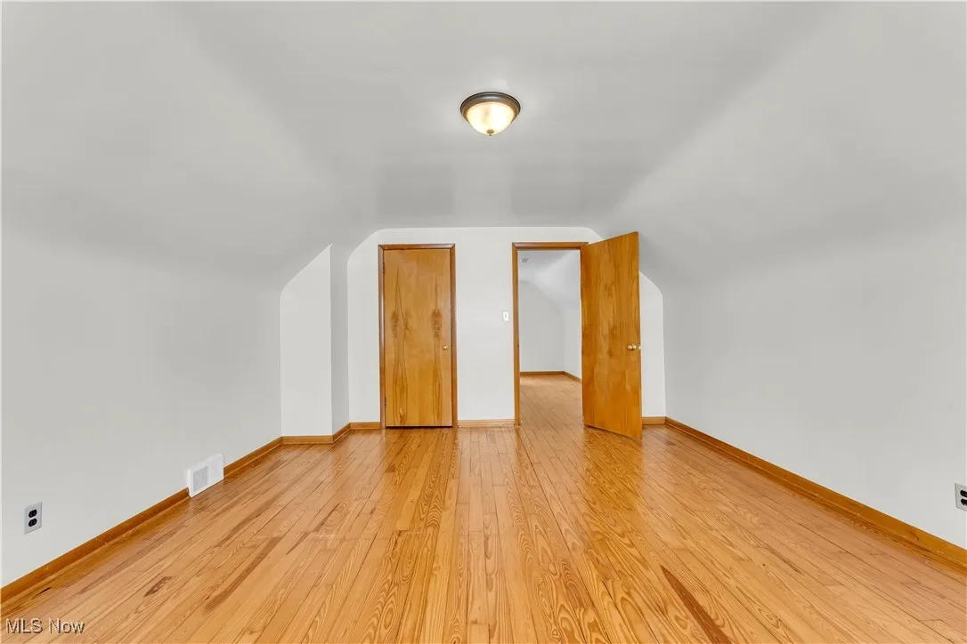 Additional living space with light wood-style flooring and lofted ceiling