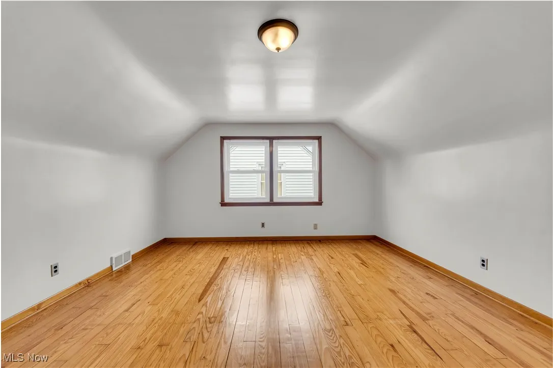 Bonus room featuring light wood-style floors and lofted ceiling