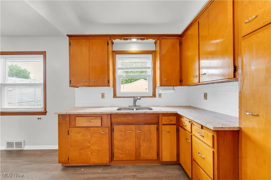 Kitchen featuring wood finished floors, tasteful backsplash, and brown cabinetry