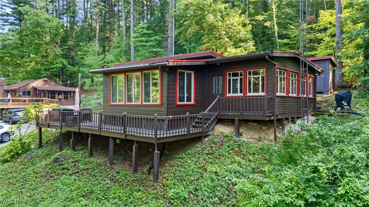 View of front of home featuring a wooden deck and a wooded view