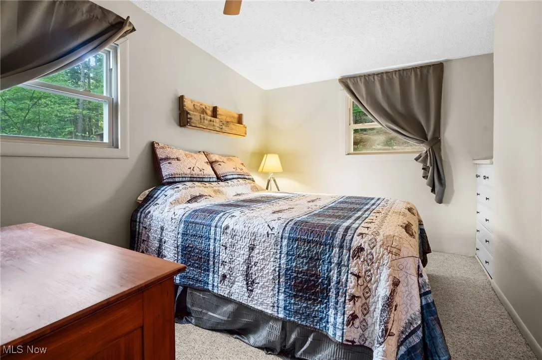 Carpeted bedroom with a ceiling fan and a textured ceiling