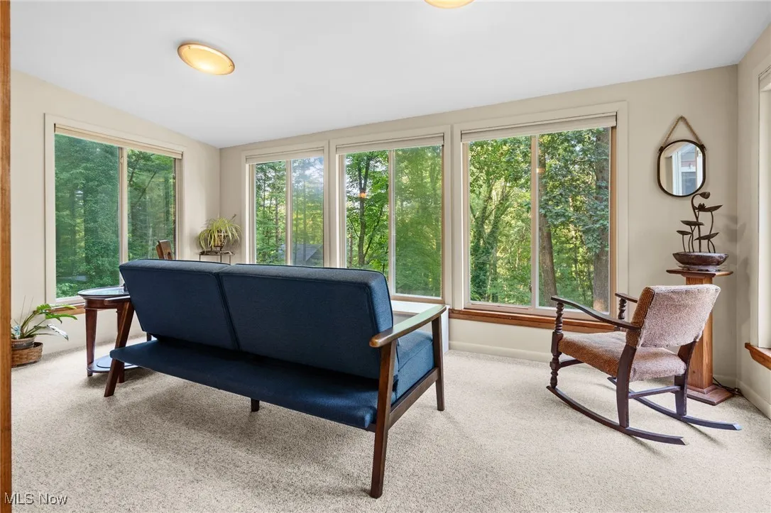 Living room with plenty of natural light, light colored carpet, and lofted ceiling