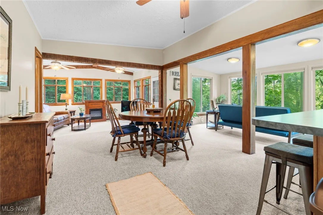 Dining area featuring a ceiling fan, carpet flooring, a glass covered fireplace, and a textured ceiling