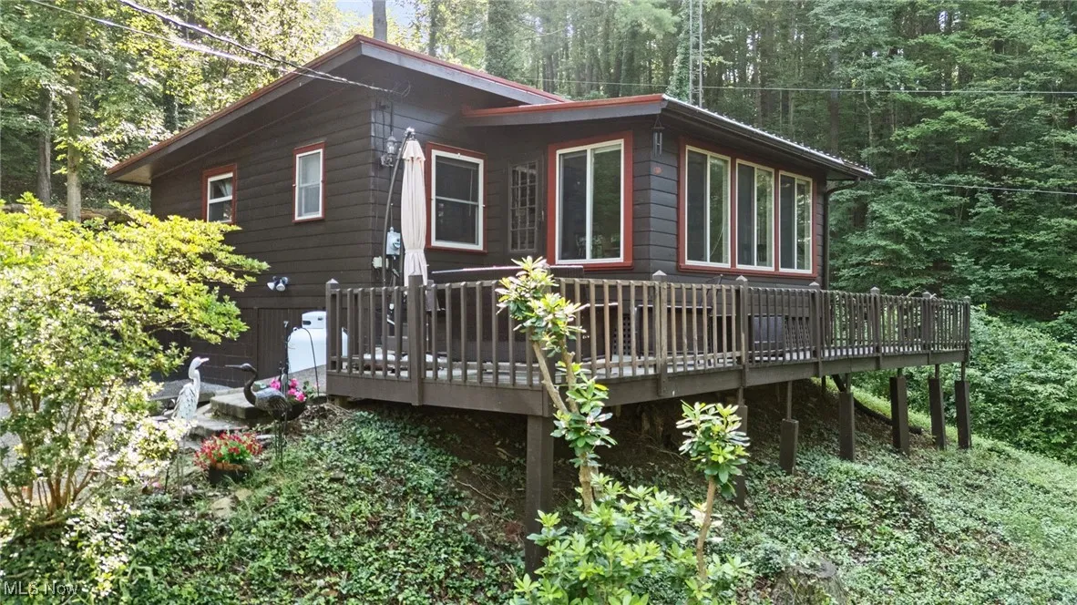 View of side of home featuring a deck and a forest view