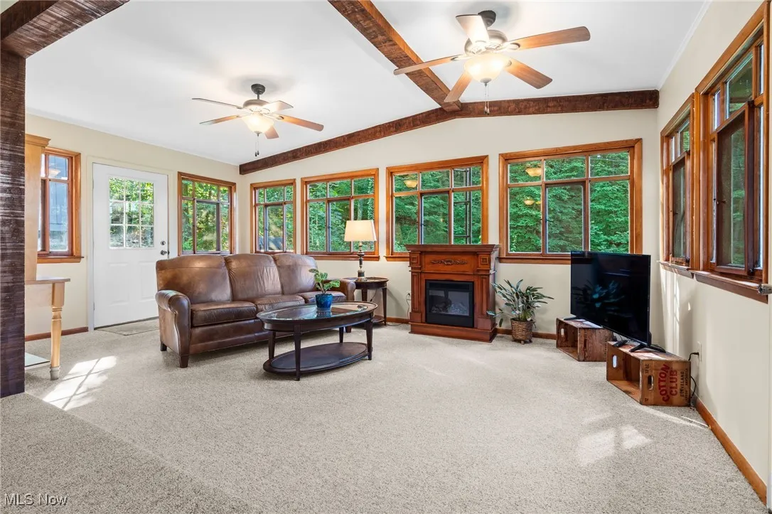 Carpeted living room featuring ceiling fan and a glass covered fireplace