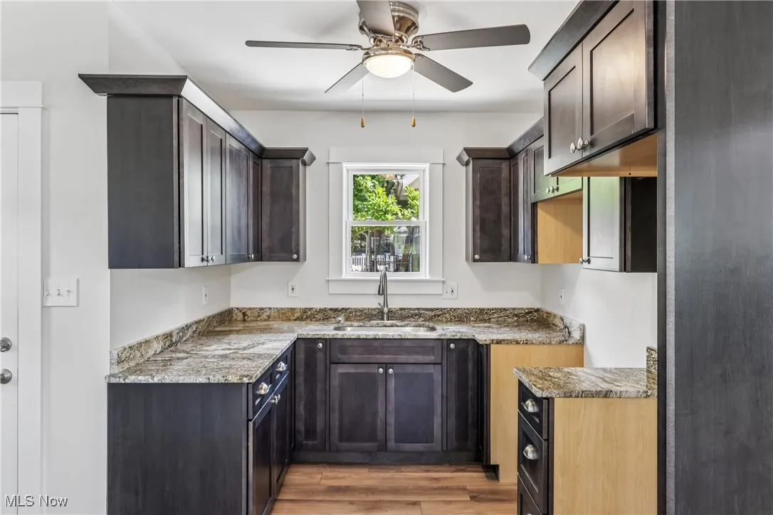 Kitchen with a sink, cupboards, Granite countertops, ceiling fan / light and LVT flooring