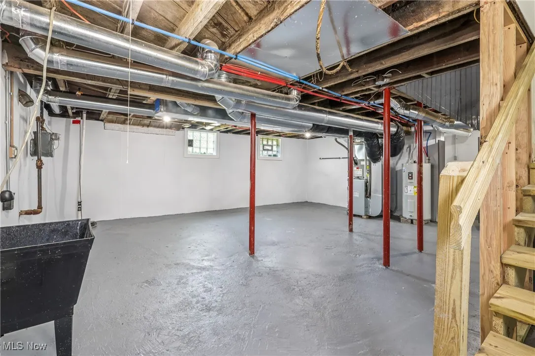 Basement with heating unit, water heater, and stairway
