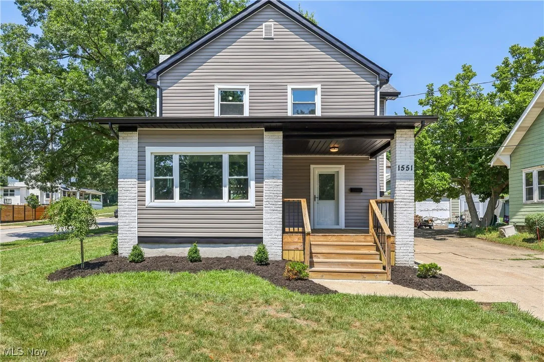 View of front of house with a porch, a front yard, and driveway