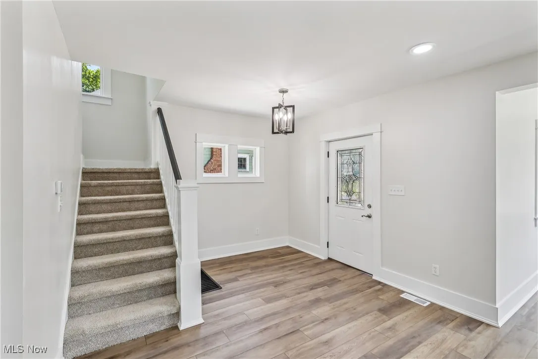 Entrance foyer featuring a healthy amount of natural light, stairway to second level, a chandelier and LVT flooring
