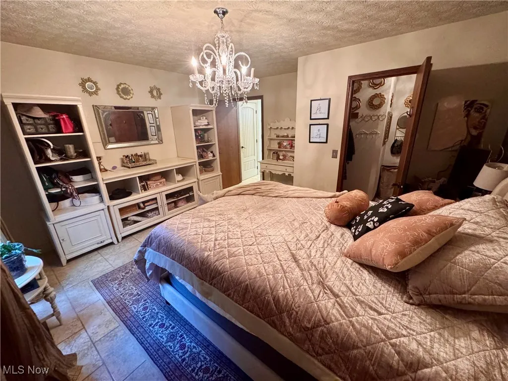 Bedroom with a textured ceiling and a chandelier