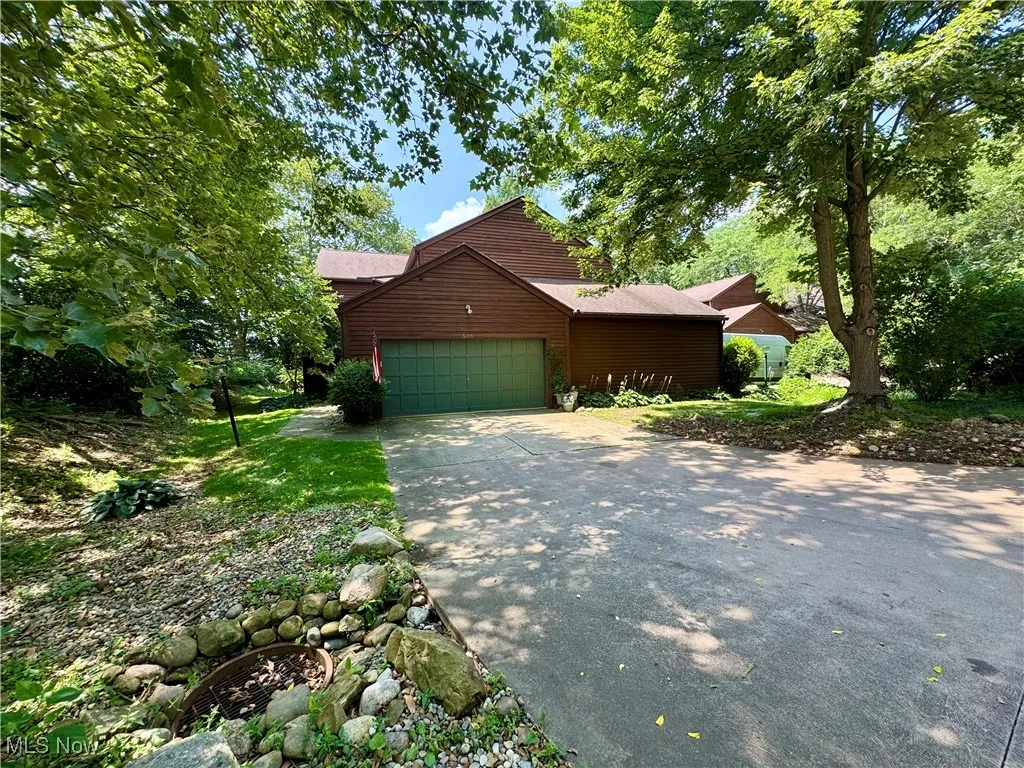 View of front of home with concrete driveway, an attached garage, and faux log siding