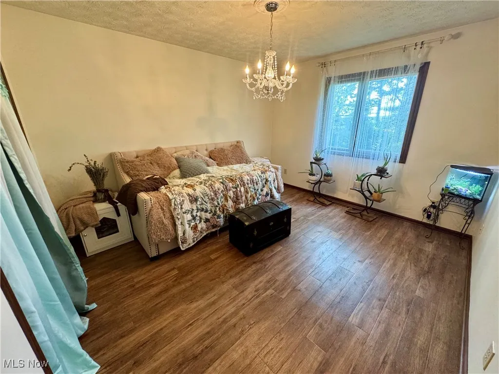Bedroom with a textured ceiling, wood finished floors, and a chandelier