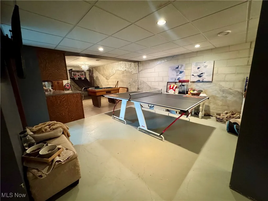 Recreation room featuring finished concrete floors, concrete block wall, pool table, recessed lighting, and a paneled ceiling