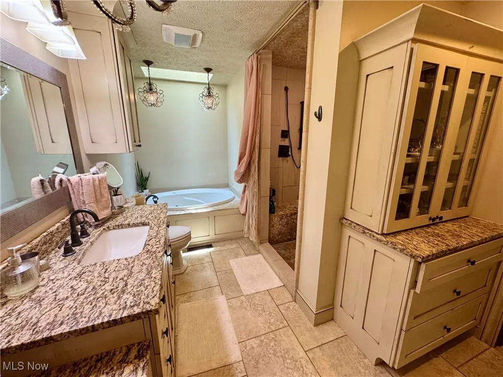 Bathroom featuring a tile shower, vanity, a tub to relax in, and a textured ceiling