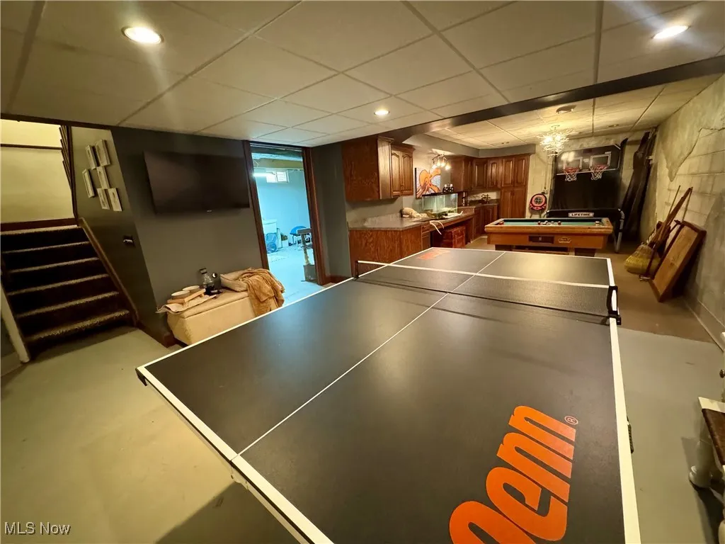 Playroom with finished concrete flooring, pool table, and a drop ceiling
