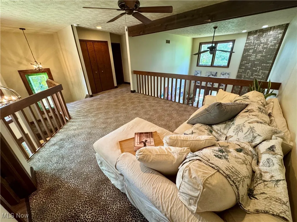 Living area with a ceiling fan, carpet, and a textured ceiling