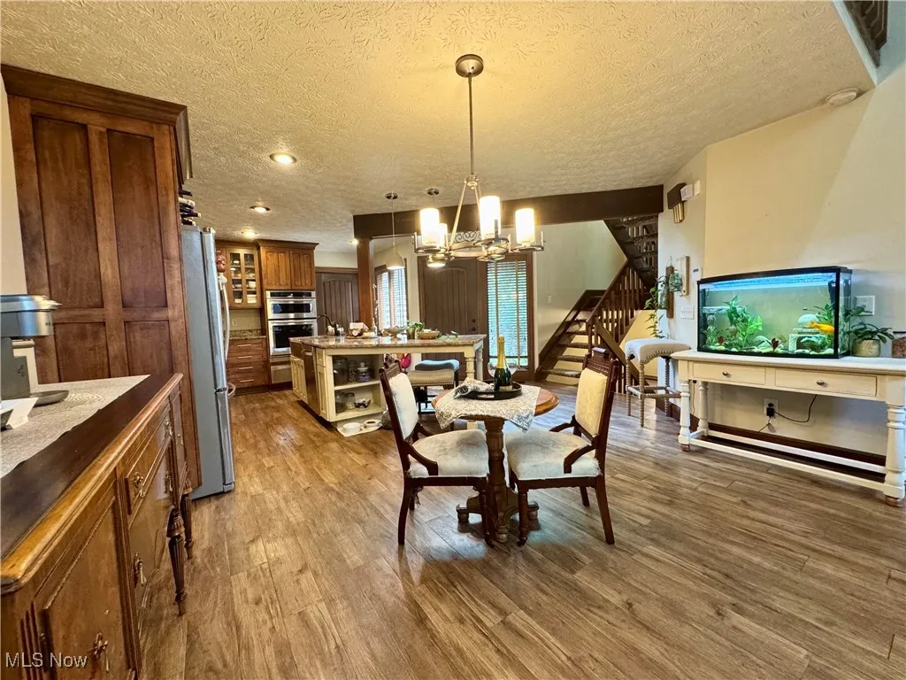 Dining room with a chandelier, stairway, wood finished floors, a textured ceiling, and recessed lighting