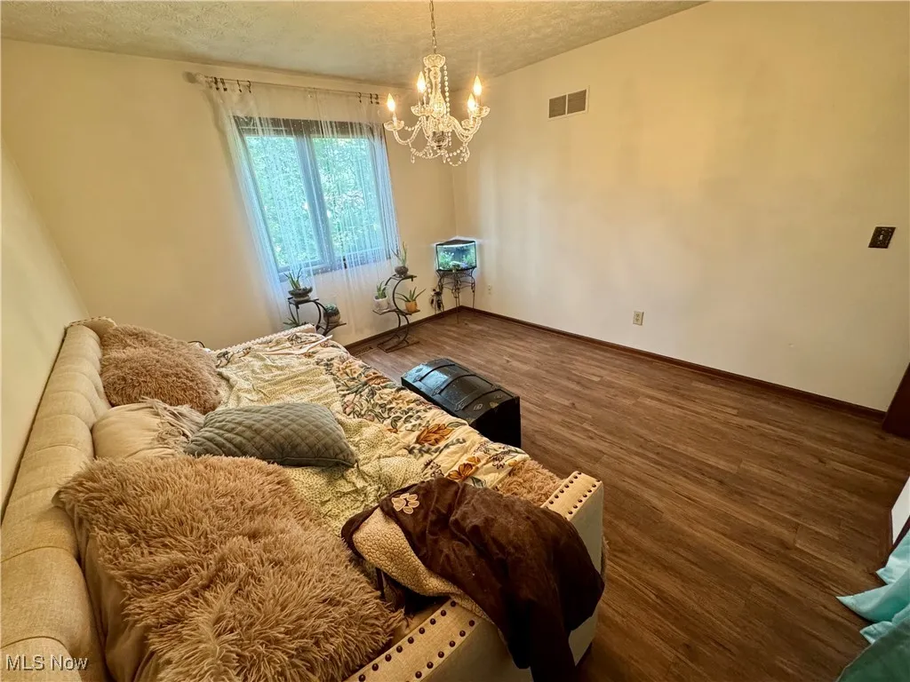 Bedroom with a chandelier, a textured ceiling, and wood finished floors