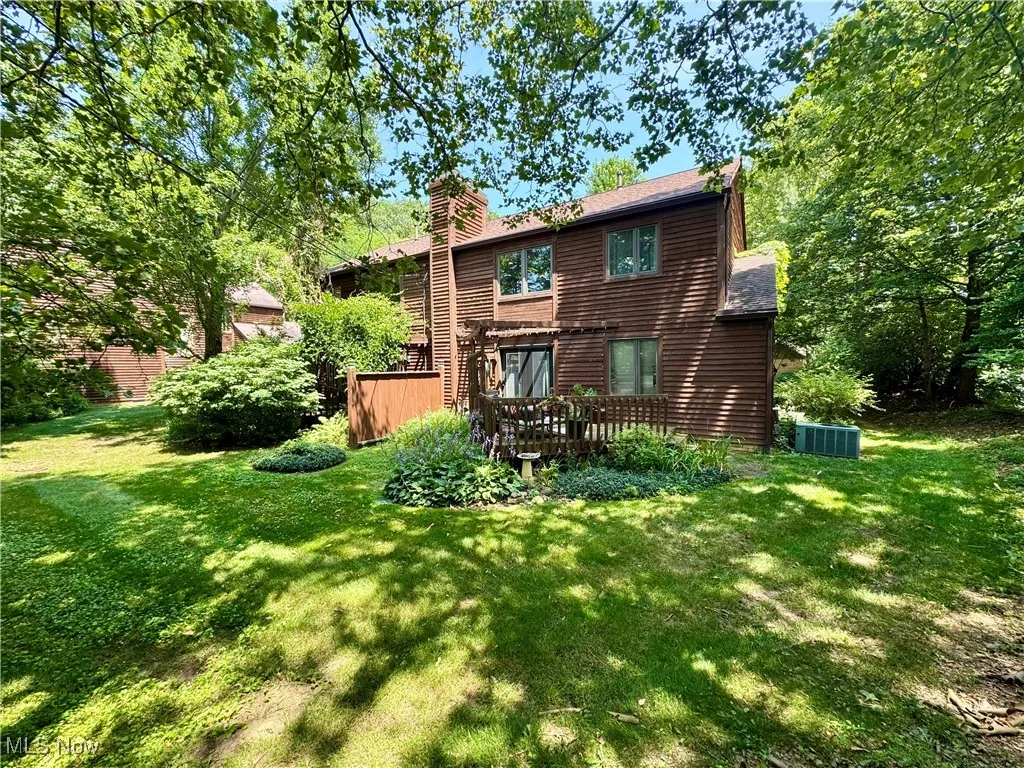 Rear view of property with a chimney, a lawn, and a wooden deck