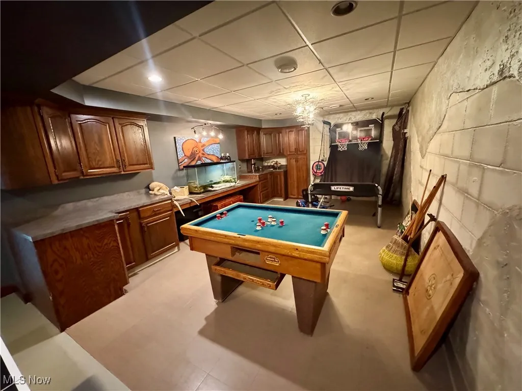 Rec room with billiards table, a paneled ceiling, and concrete block wall