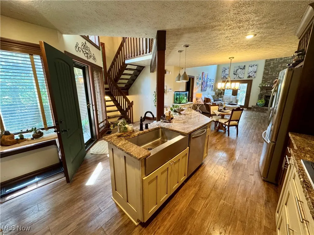 Kitchen with dark wood-style floors, a textured ceiling, dark stone countertops, appliances with stainless steel finishes, and open floor plan