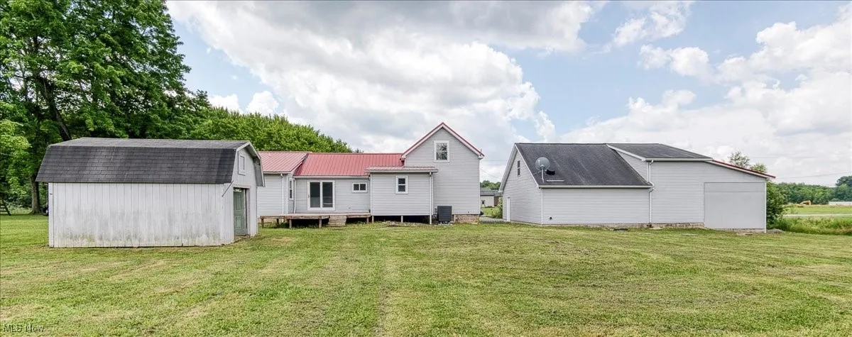 Back of property featuring a gambrel roof, a yard, a shed, and a metal roof