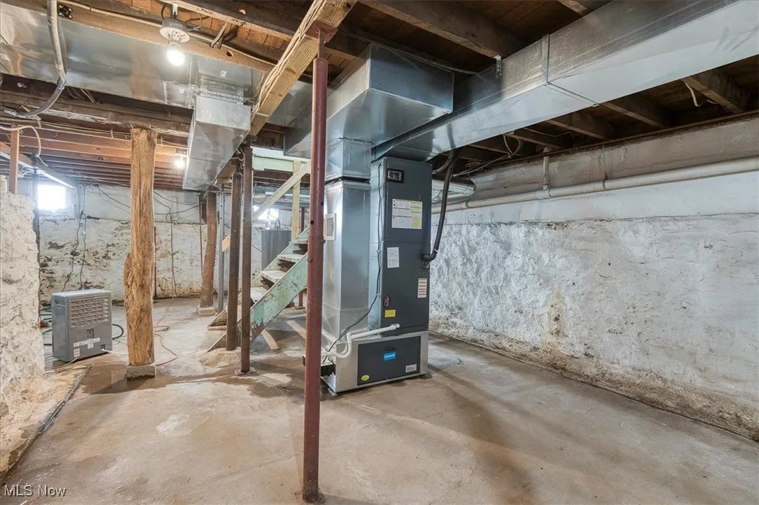 Below grade area featuring heating unit and stairs
