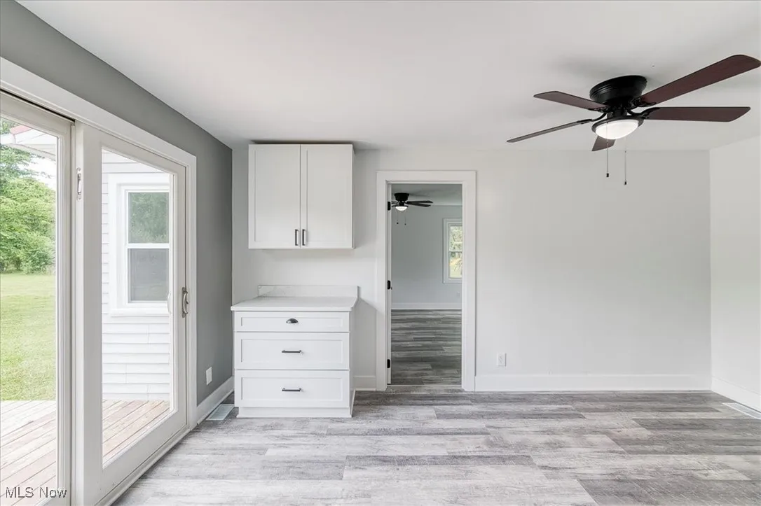 Kitchen featuring light wood-style floors, ceiling fan, white cabinetry, and light countertops