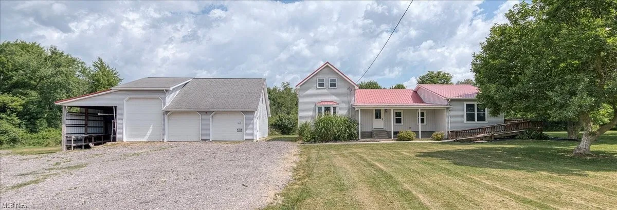 View of front facade featuring an outbuilding, a garage, a front yard, and a metal roof