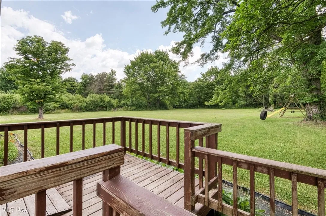 Wooden terrace featuring a yard and view of wooded area