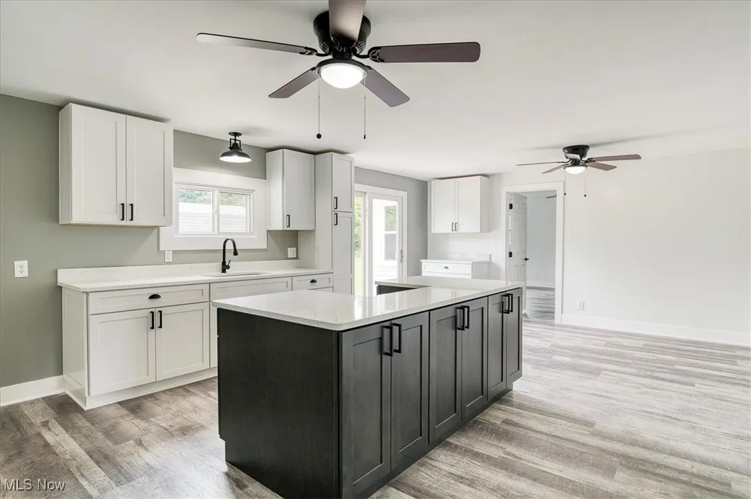 Kitchen with a ceiling fan, white cabinets, light countertops, and light wood-type flooring