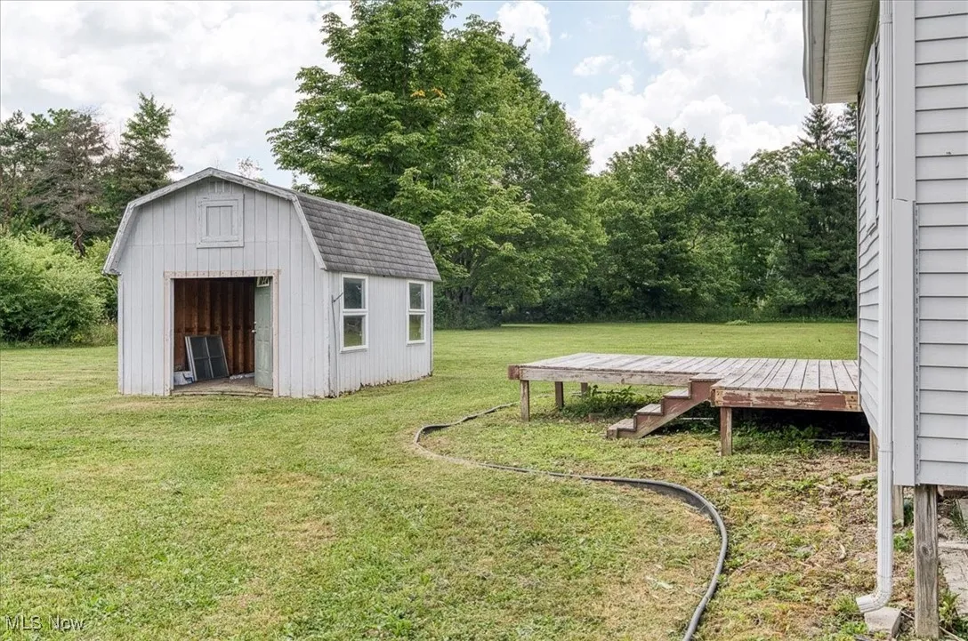 View of green lawn with a shed and a wooden deck