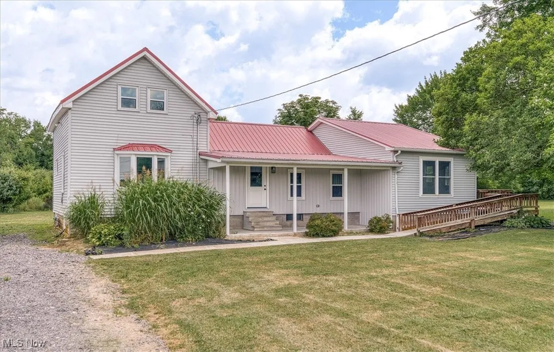 View of front of house featuring board and batten siding, a front yard, a metal roof, and a porch
