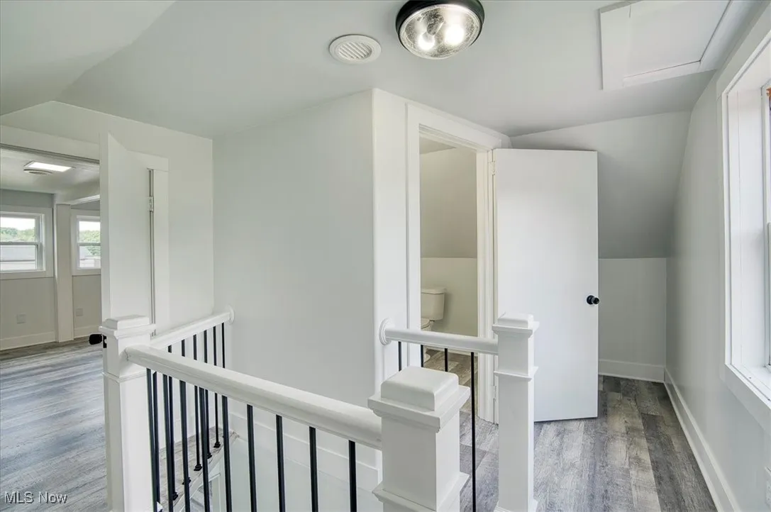 Corridor featuring an upstairs landing, wood finished floors, and lofted ceiling