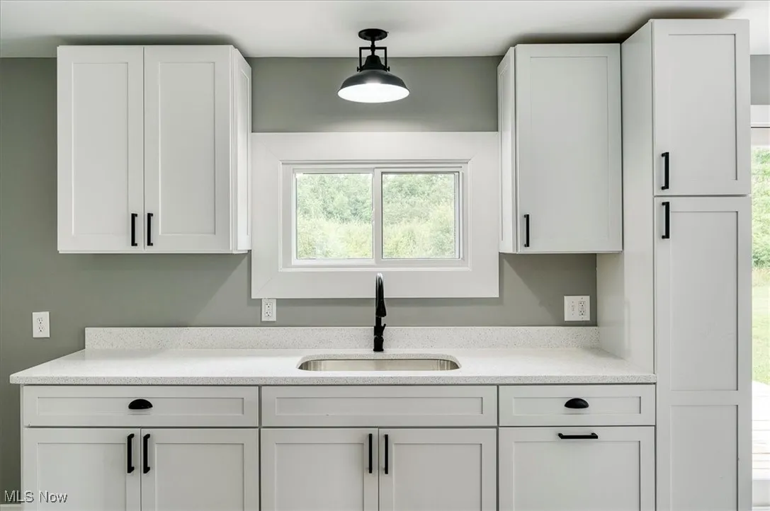 Kitchen with white cabinets, light countertops, and hanging light fixtures