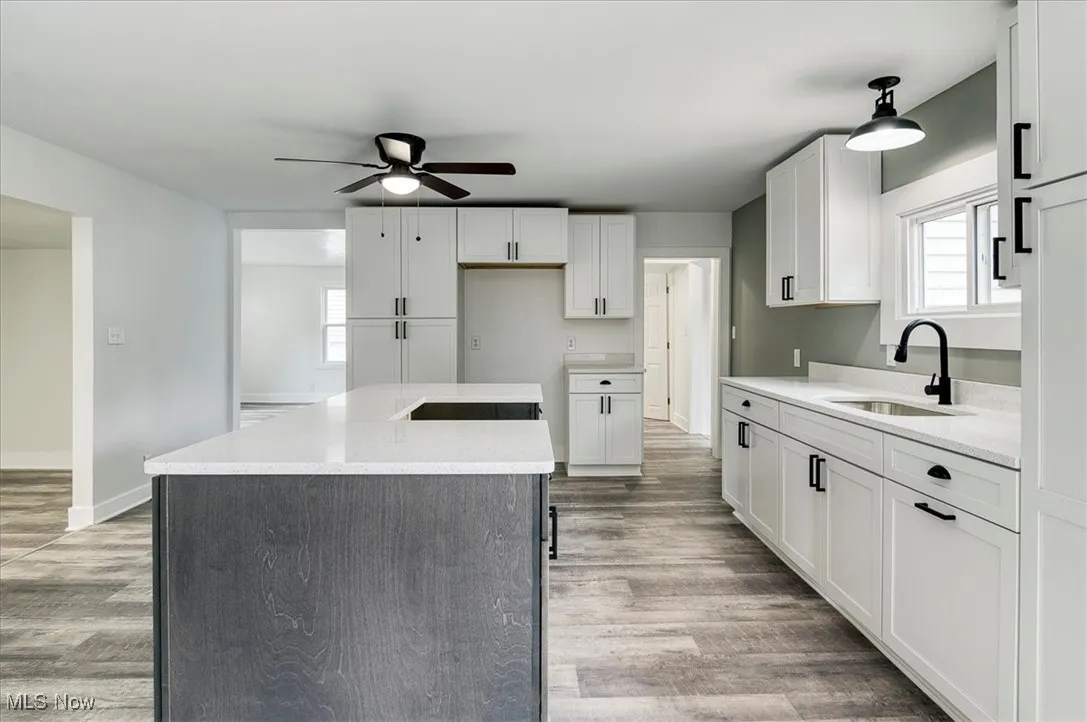 Kitchen featuring a ceiling fan, a kitchen island, white cabinets, and light wood-style floors