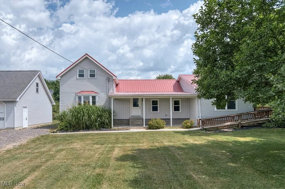 View of front of property featuring a metal roof, a front yard, a porch, and board and batten siding
