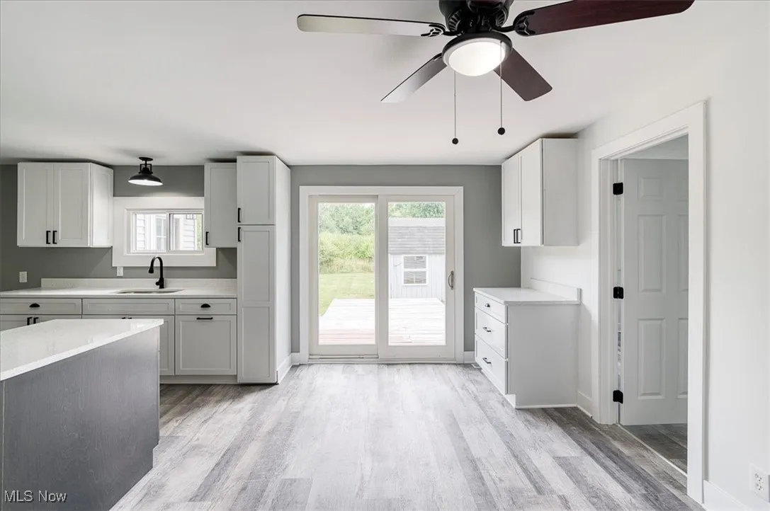 Kitchen featuring light countertops, light wood-style flooring, ceiling fan, and white cabinetry