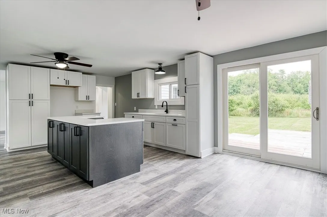 Kitchen featuring a ceiling fan, wood finished floors, light countertops, and white cabinets
