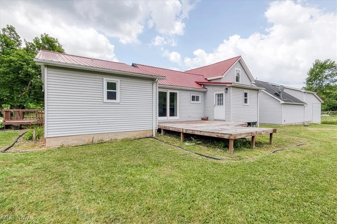 Back of house with a deck, a metal roof, and a yard