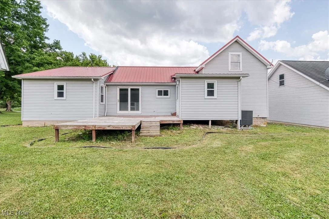 Rear view of house featuring a metal roof, a deck, and a lawn