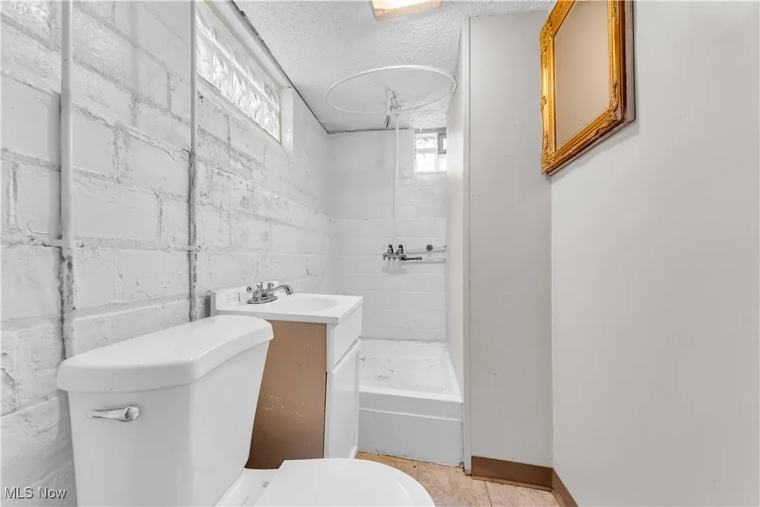 Full bath with a stall shower, healthy amount of natural light, vanity, and a textured ceiling
