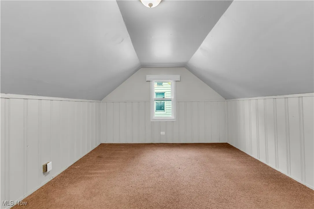 Bonus room featuring carpet, lofted ceiling, and a decorative wall