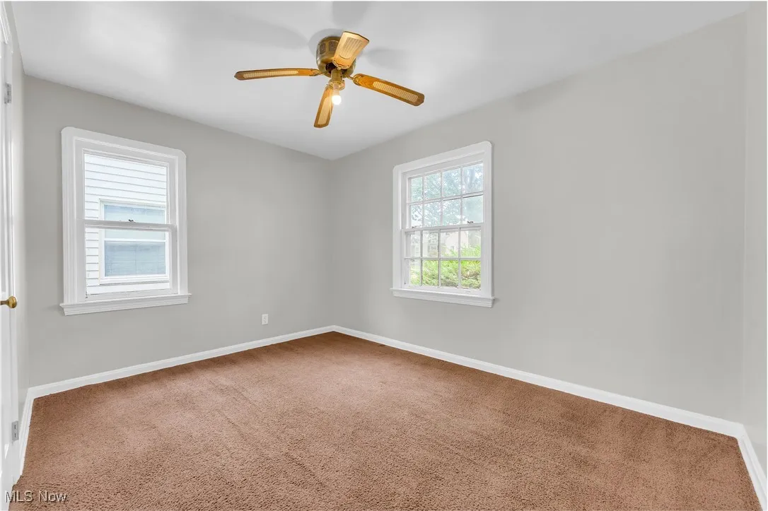 Empty room featuring carpet flooring and a ceiling fan