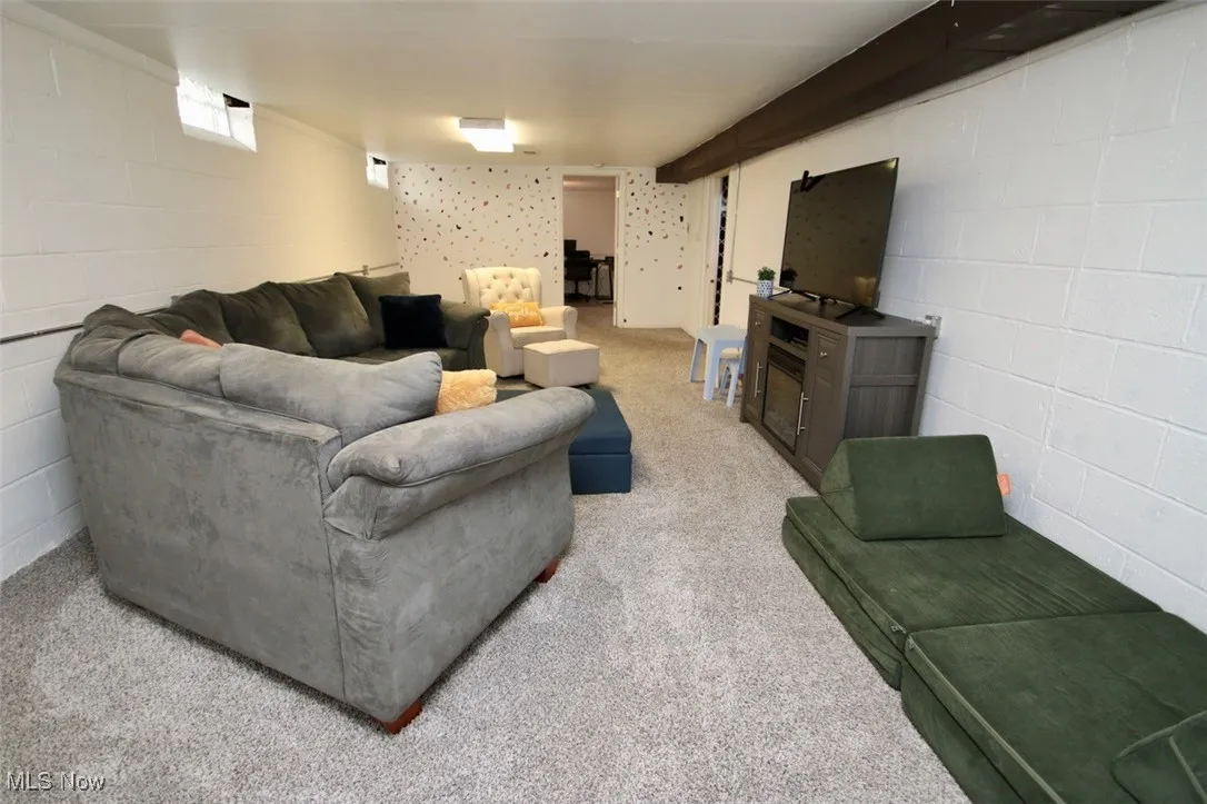 Carpeted living room featuring concrete block wall