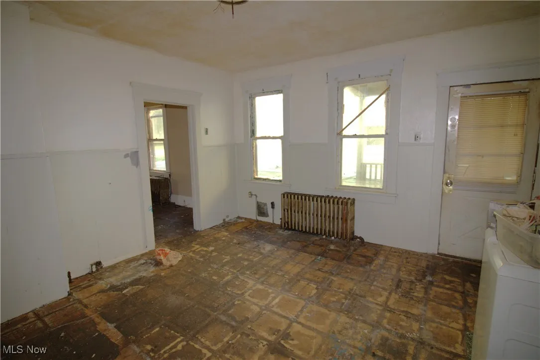 Spare room featuring a wainscoted wall, washer / dryer, and radiator