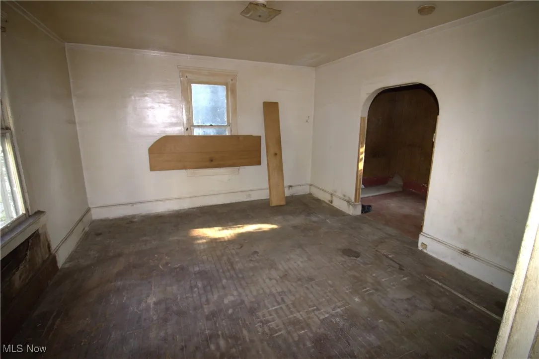 Spare room with arched walkways, plenty of natural light, and crown molding