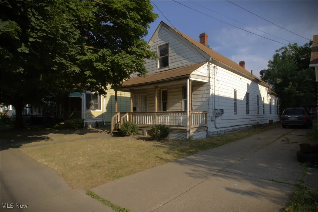 View of front facade featuring a porch, a chimney, concrete driveway, and a front yard