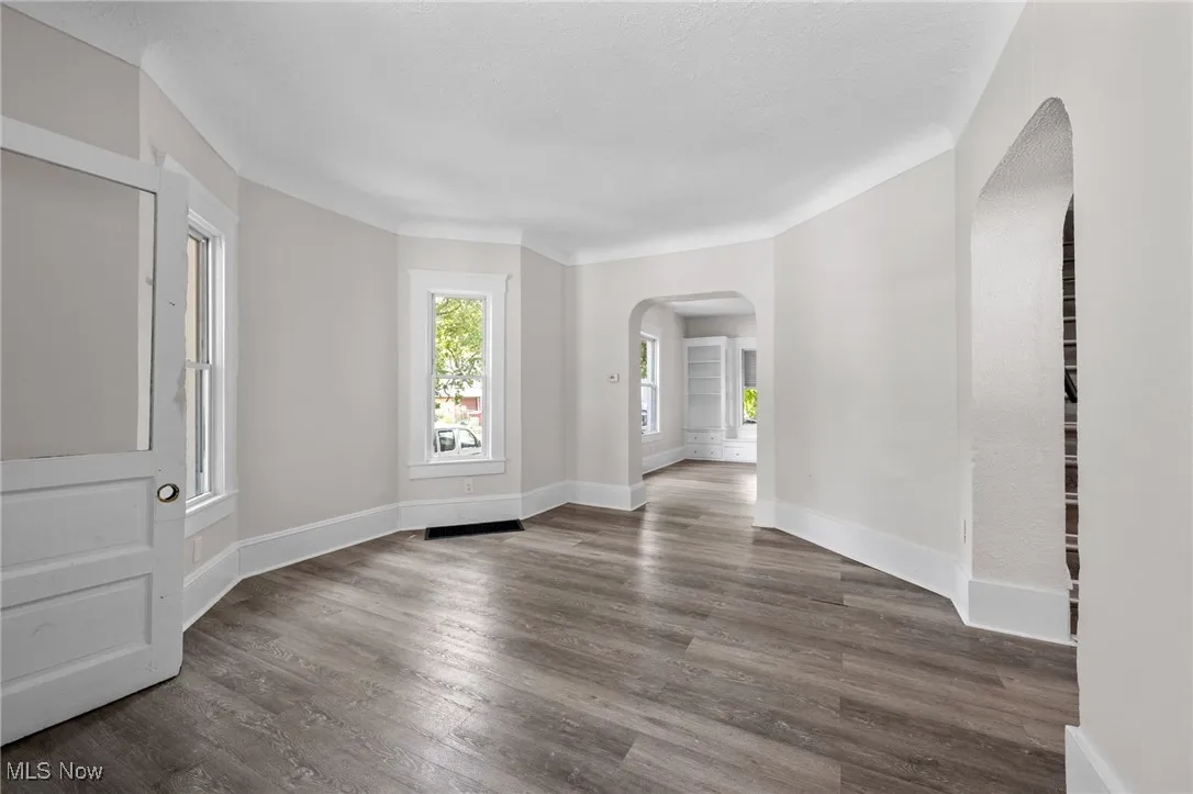 Living room with arched walkways and wood style floors